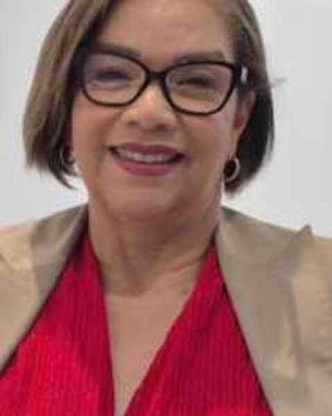 Dra. Neuza Santos usando óculos, blazer bege e top vermelho